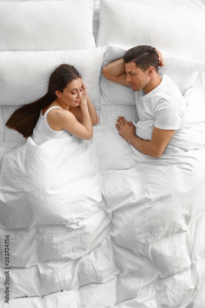 Fototapeta premium Lovely young couple sleeping in large bed, above view