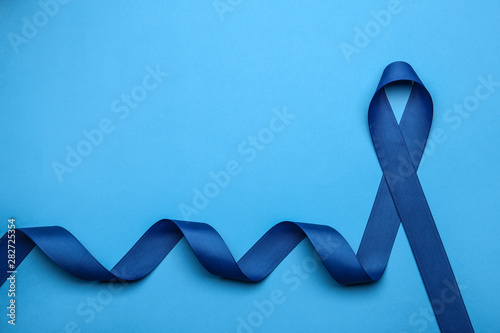 Blue awareness ribbon on color background, top view with space for text. Symbol of social and medical issues photo