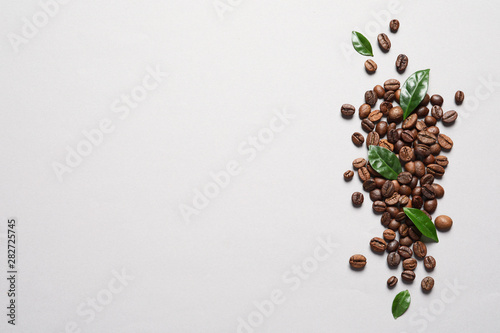 Fresh green coffee leaves and beans on light background, flat lay. Space for text