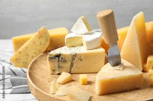 Different types of delicious cheese in wooden plate, closeup