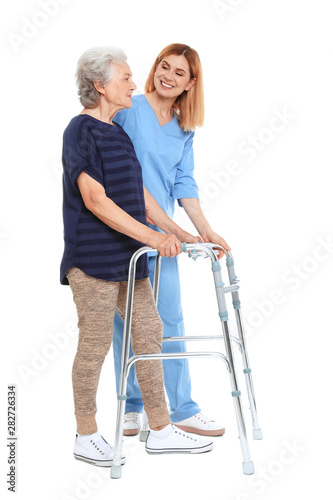 Canvas Print Caretaker helping elderly woman with walking frame on white background