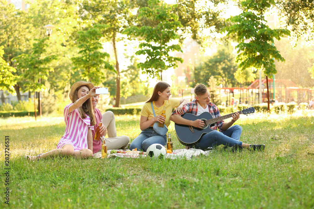 Young people enjoying picnic in park on summer day Young people enjoying picnic in park on summer day