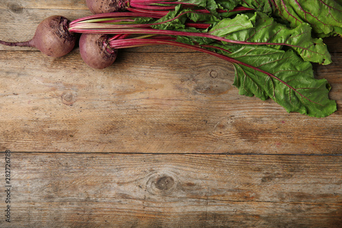 Fresh beets with leaves on wooden table, flat lay. Space for text