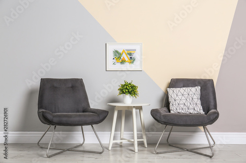 Room interior with modern chairs and table near color wall © New Africa