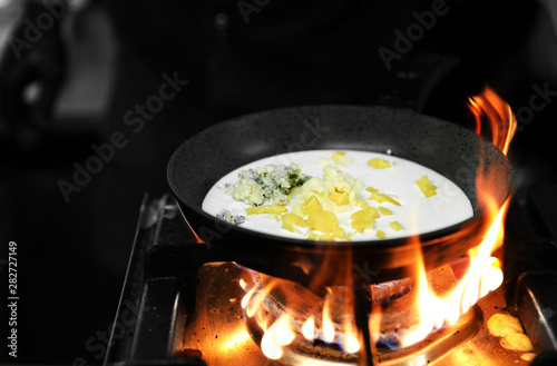 Frying pan with cheese and cream on stove