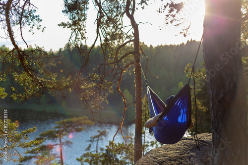Moody sunset photo of a man in a hammock. Shallow depth of field and a low angle.