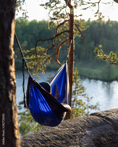 Moody sunset photo of a man in a hammock. Shallow depth of field and a low angle.