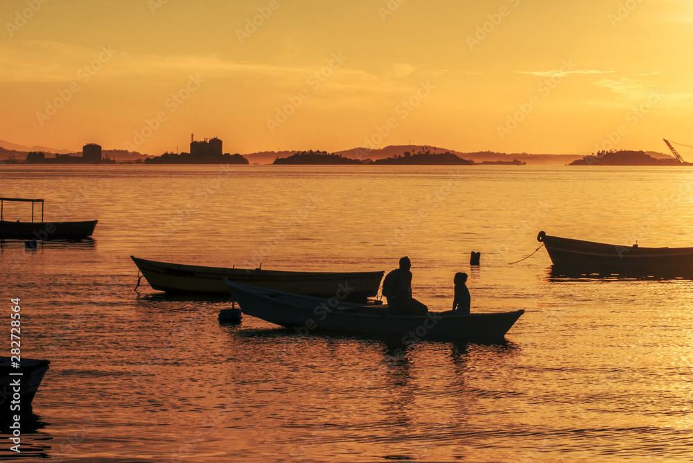 Silhouette of father and daughter in the boat and with sunset