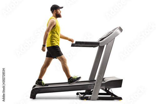 Foto Bearded guy in sportswear walking on a treadmill with an incline