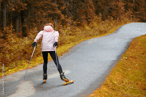 Woman cross-country skiing with roller ski in park photo