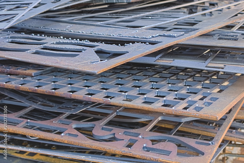 Perforated metal sheets after laser cutting lie on each other. Metalworking waste prepared for recycling. Perforated metal sheets after laser cutting lie on each other. Metalworking waste prepared for recycling.