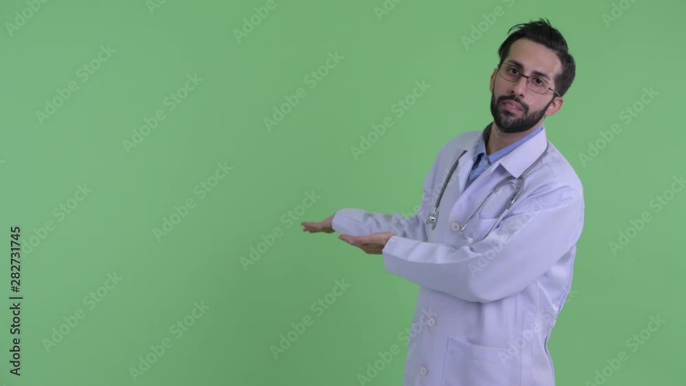 Stressed young bearded Persian man doctor showing to back Stressed young bearded Persian man doctor showing to back