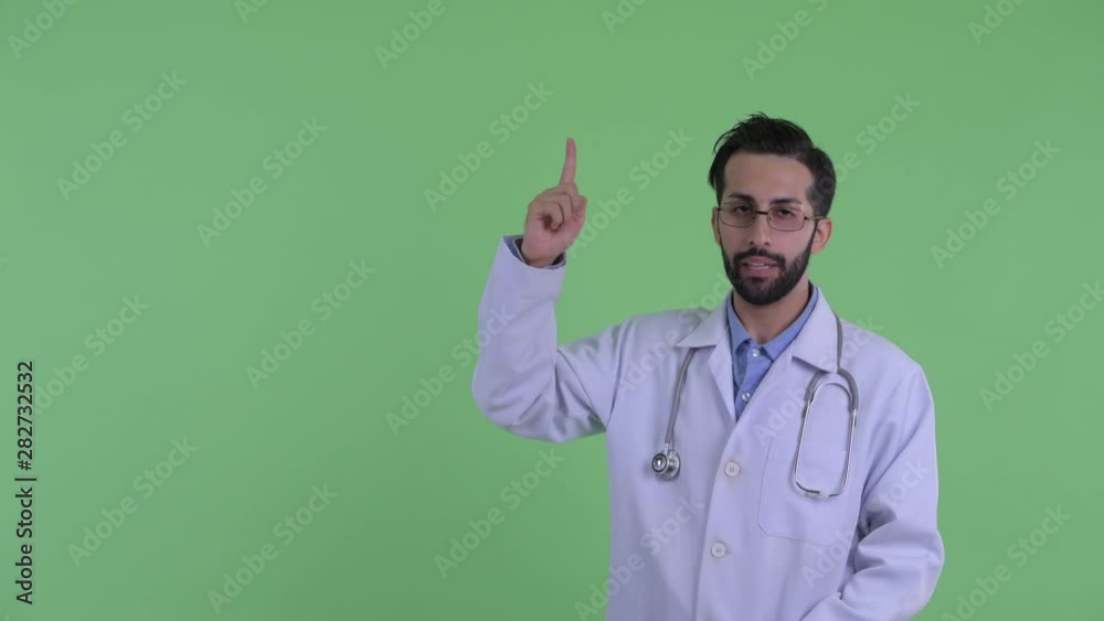 Stressed young bearded Persian man doctor pointing up Stressed young bearded Persian man doctor pointing up