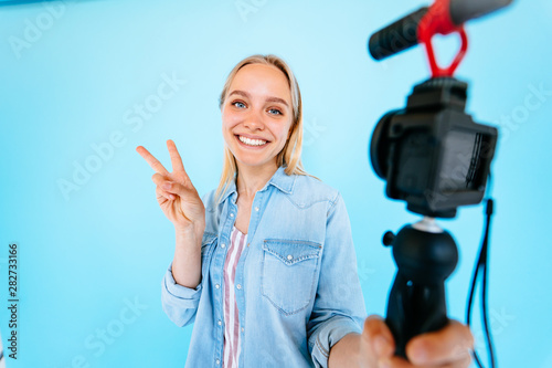 Beautiful girl blogger relieves itself at camera isolated blue background