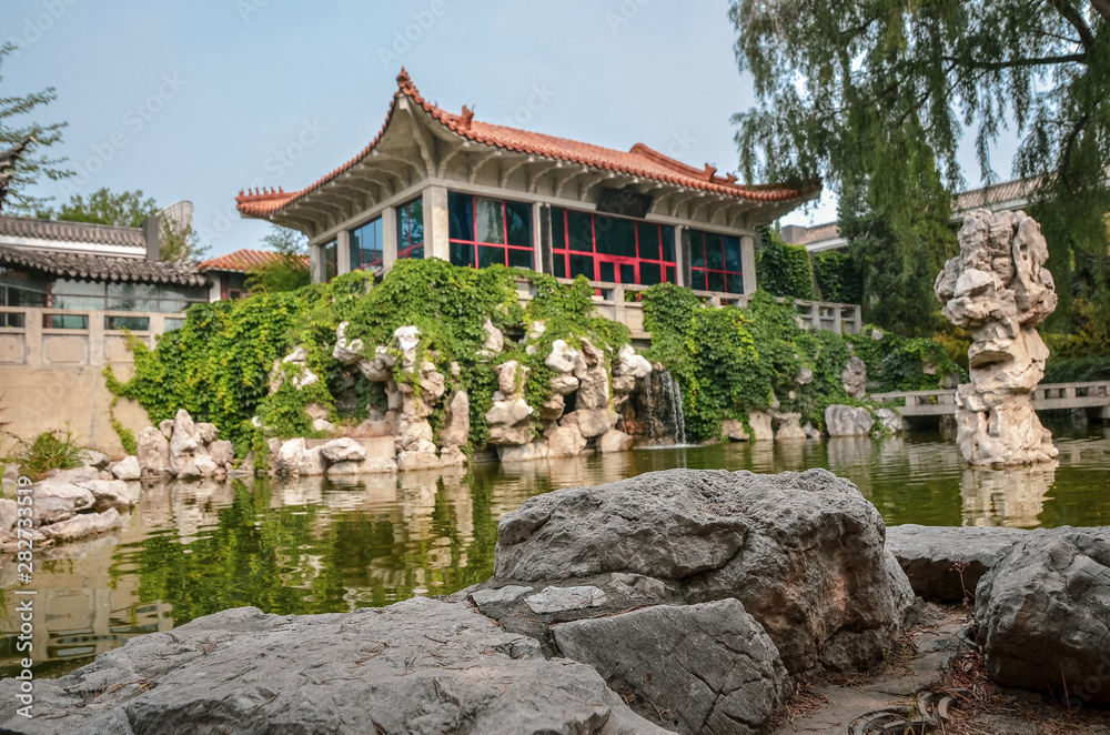 Сozy chinese garden with a pond, pavillion, and a waterfall. Close up. Сozy chinese garden with a pond, pavillion, and a waterfall. Close up.