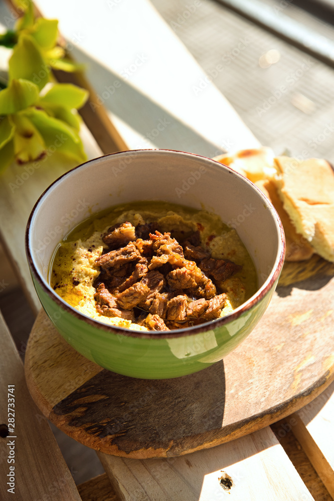Fototapeta premium Chickpea hummus with stewed beef in a plate on wooden background