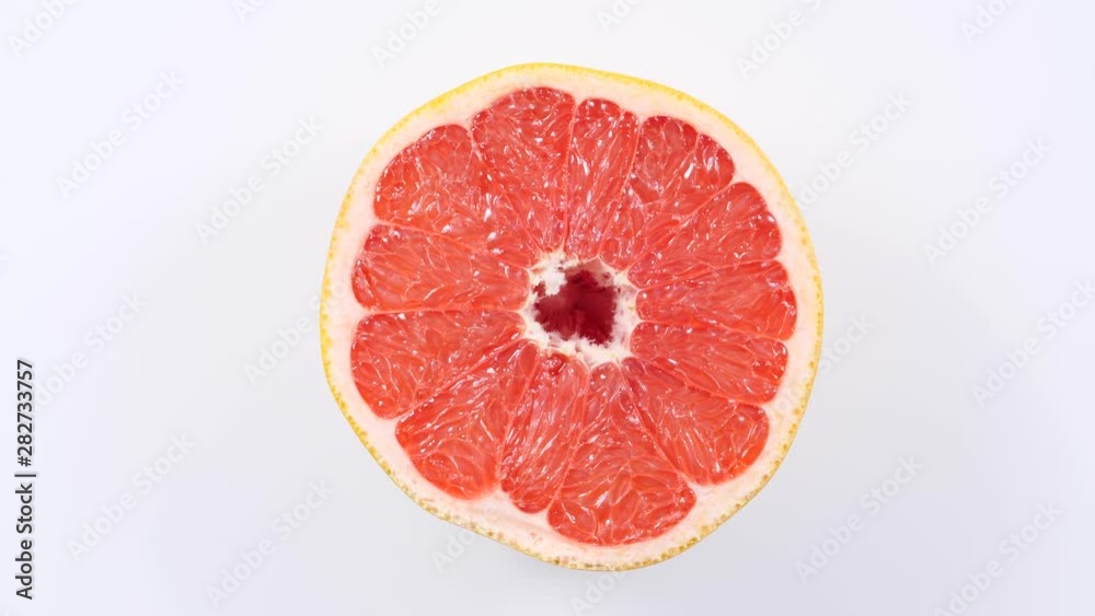 Fresh half of grapefruit citrus fruit on plate rotating. Healthy eating, weight loss, light meal. Top view Fresh half of grapefruit citrus fruit on plate rotating. Healthy eating, weight loss, light meal. Top view