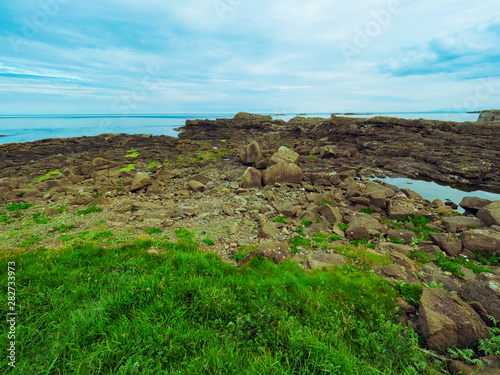 Scenic beach with rocks and grass at the coast of Portrush, on summer monirng time ,Northern Ireland