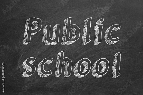 Hand drawing "Public school" on black chalkboard. 