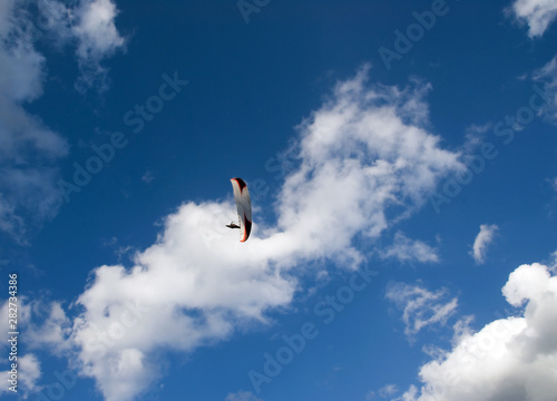 Photo of a parachutist over blue sky with clouds