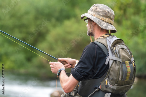 Fisherman fishing on the River, holding Fishing Rod .
