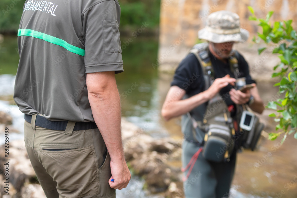 Police officer or Ranger checking fisherman license in river. Fishing inspection. Law . Police officer or Ranger checking fisherman license in river. Fishing inspection. Law .