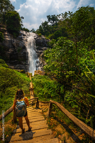 Tourist walks down wooden stairs at Wachirathan waterfall in Doi Inthanon National Park near Chiang Mai Thailand