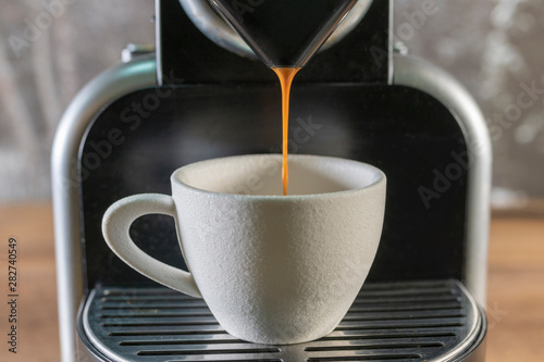 An espresso machine pouring coffee into a white cup