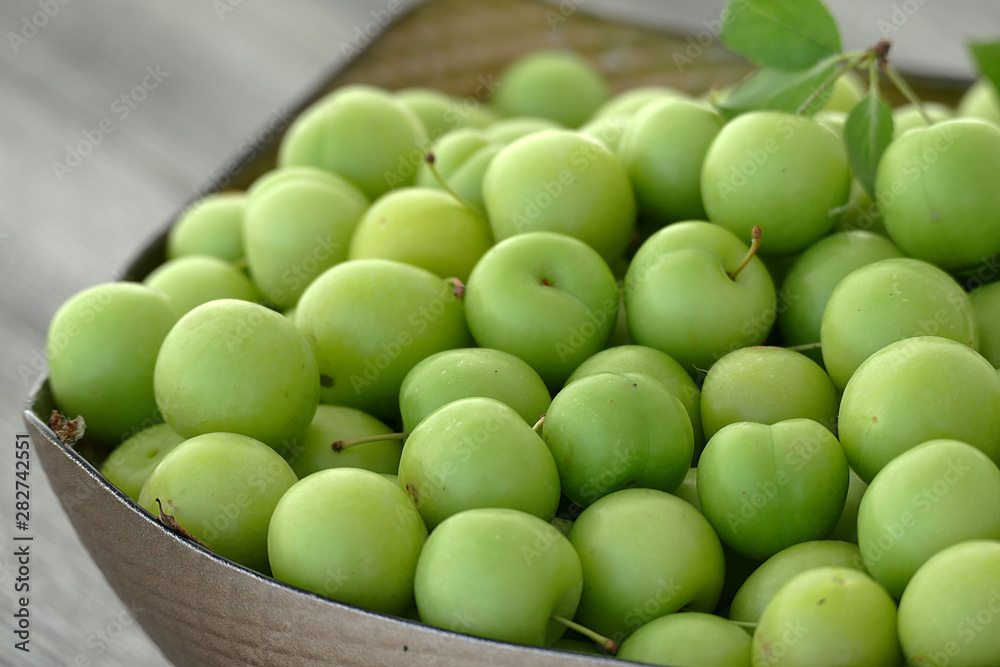 close-up of green sour plums, a container of plums, fresh green plums,