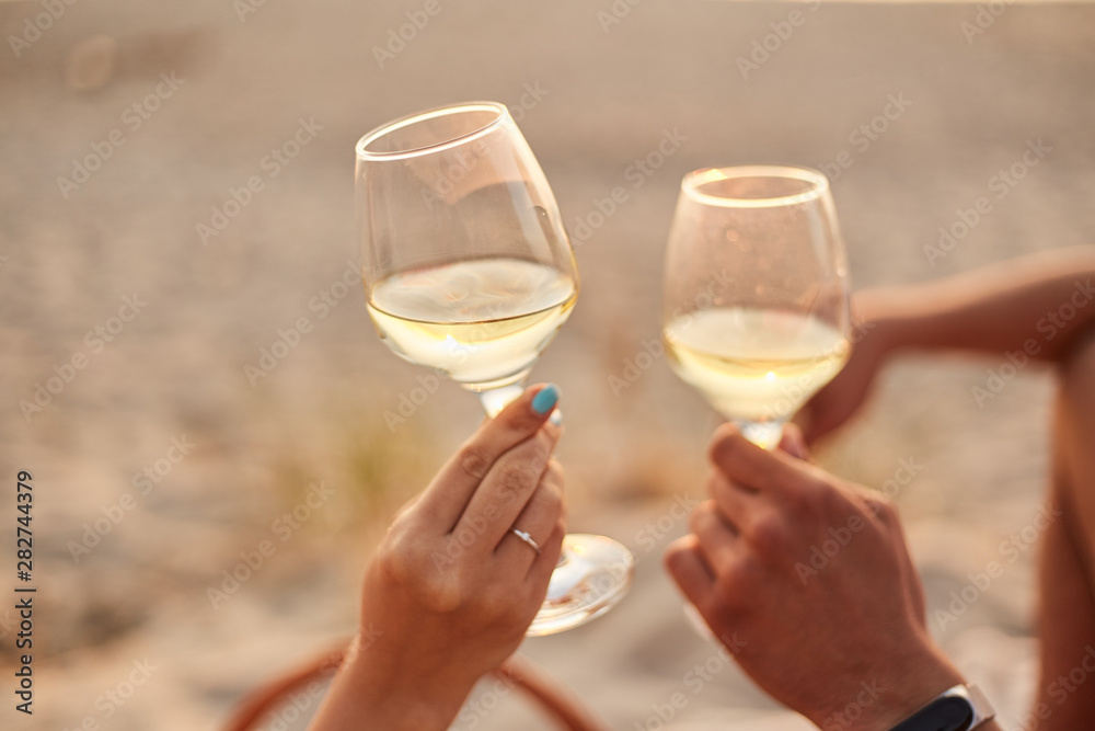 Couple clinking glasses of champagne at sunset