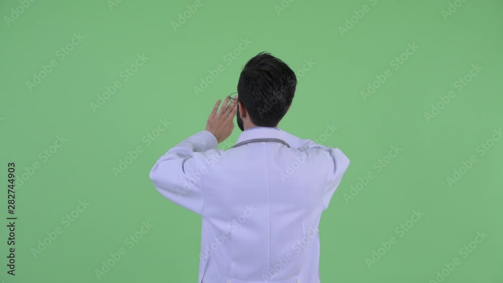 Profile view of young bearded Persian man doctor touching something Profile view of young bearded Persian man doctor touching something