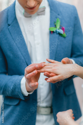 The groom puts the ring on the bride. Hands close up. vertical photo.