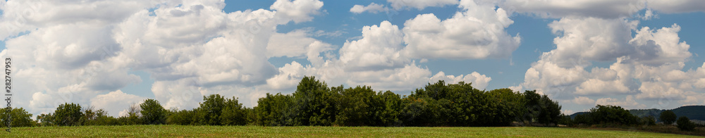 Fields and forests of Bulgaria before the rain. Cumuliform cloudscape on blue sky. The terrain in southern Europe. Fantastic skies on the planet earth. The sun is hidden. Panorama. Fields and forests of Bulgaria before the rain. Cumuliform cloudscape on blue sky. The terrain in southern Europe. Fantastic skies on the planet earth. The sun is hidden. Panorama.