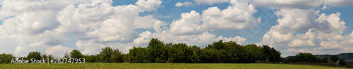 Fields and forests of Bulgaria before the rain. Cumuliform cloudscape on blue sky. The terrain in southern Europe. Fantastic skies on the planet earth. The sun is hidden. Panorama.