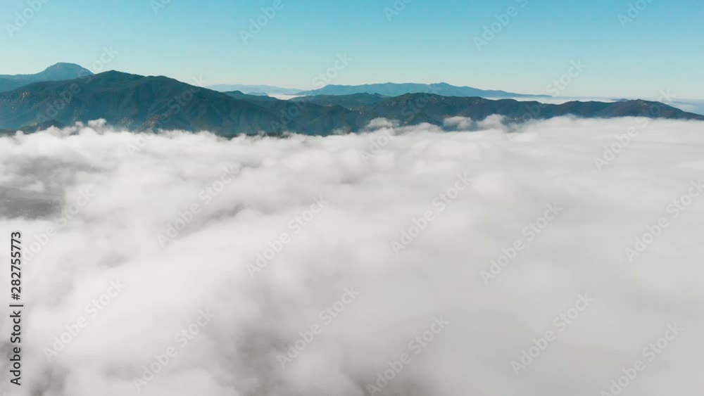 Flying abovve the clouds with a mountain range in the distance Flying abovve the clouds with a mountain range in the distance