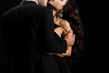 cropped view of bearded man undressing young woman isolated on black