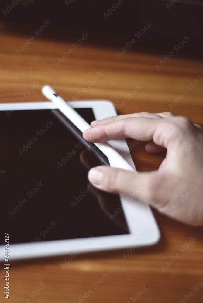 Tablet computer and pencil on wooden dark background. black screen similar to pad display. computer. Man's hand draws. Tablet computer and pencil on wooden dark background. black screen similar to pad display. computer. Man's hand draws.