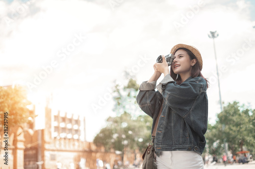 Smiling woman traveler with backpack holding vintage camera on holiday in thapae gate landmark chiang mai thailand,relaxation concept, travel concept photo