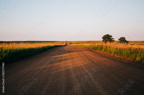 a long country highway road in rural North Dakota with a bright blue sky with clouds in the horizon