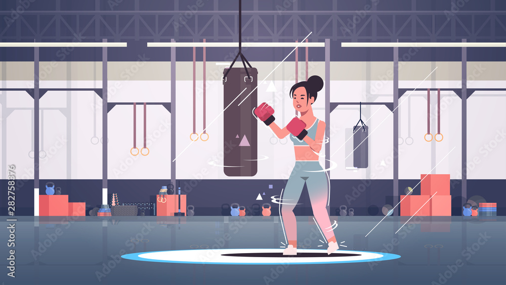 Obraz premium woman boxer doing exercises with punching bag making direct hit in red boxing gloves sportswoman fighter training workout healthy lifestyle concept modern gym sport club interior horizontal