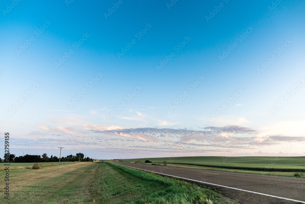 a long country highway rural highway road in North Dakota at sunset with a colorful sky