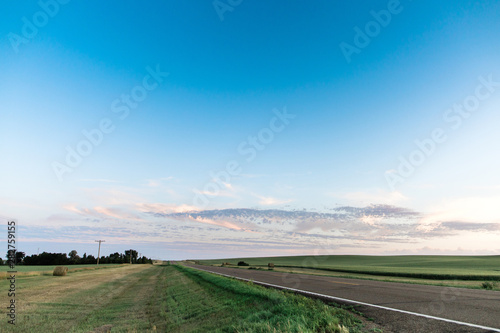 a long country highway rural highway road in North Dakota at sunset with a colorful sky