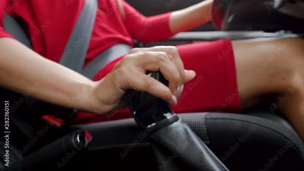 Close-up of woman driver in red dress shifts gears while driving Close-up of woman driver in red dress shifts gears while driving