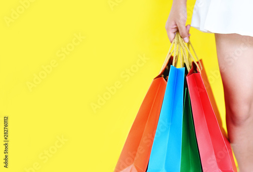 Asian young woman happy summer shopping and enjoys holiday - Pretty child girl hands holding shopping bag on yellow background