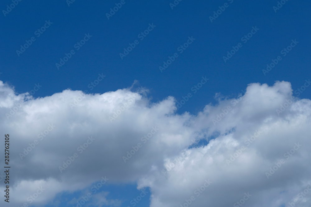 Background of blue sky with white fluffy clouds. Cropped shot, horizontal, outdoors, nobody. Concept of nature and ecology.