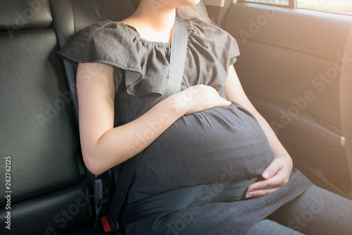 Pregnant woman wear safety seat belt in the car.