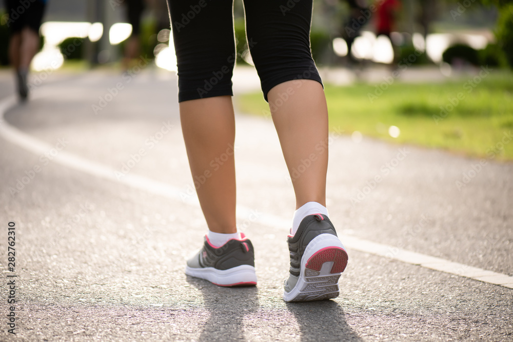 Closeup woman walking towards on the road side. Step, walk and outdoor exercise activities concept. Closeup woman walking towards on the road side. Step, walk and outdoor exercise activities concept.