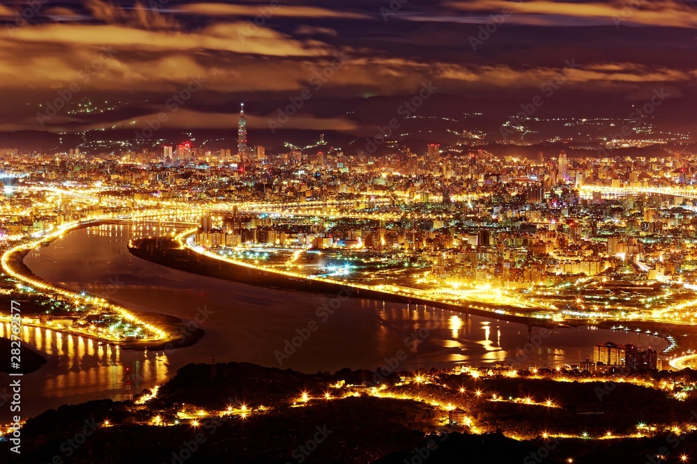 Aerial panorama of Taipei City in a blue gloomy night, with view of Guandu  plain, Tamsui River, downtown area and landmark tower in XinYi District, in evening twilight