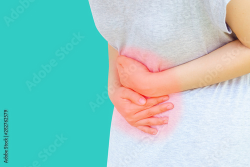 Young asian women hold hands in painful areas which may be caused by gastritis,menstruation period cramp,abdominal pain, stomach gas,cancer,liver disease,gallstones in gallbladder,food poisoning. photo