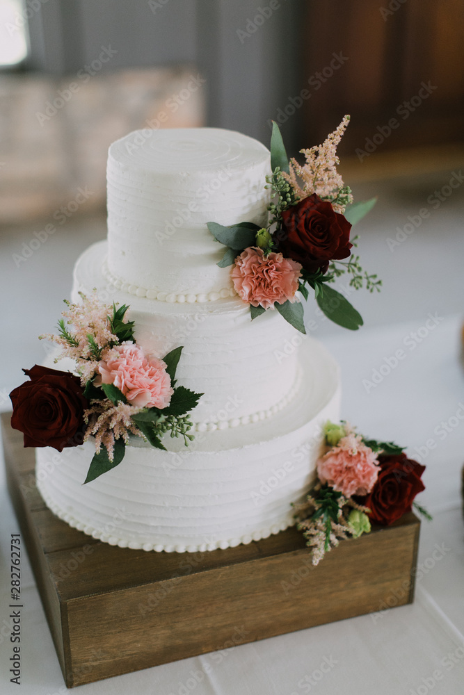 Modern White Wedding Cake with pink and red roses, stacked cake with  vanilla icing, wedding reception Stock Photo | Adobe Stock